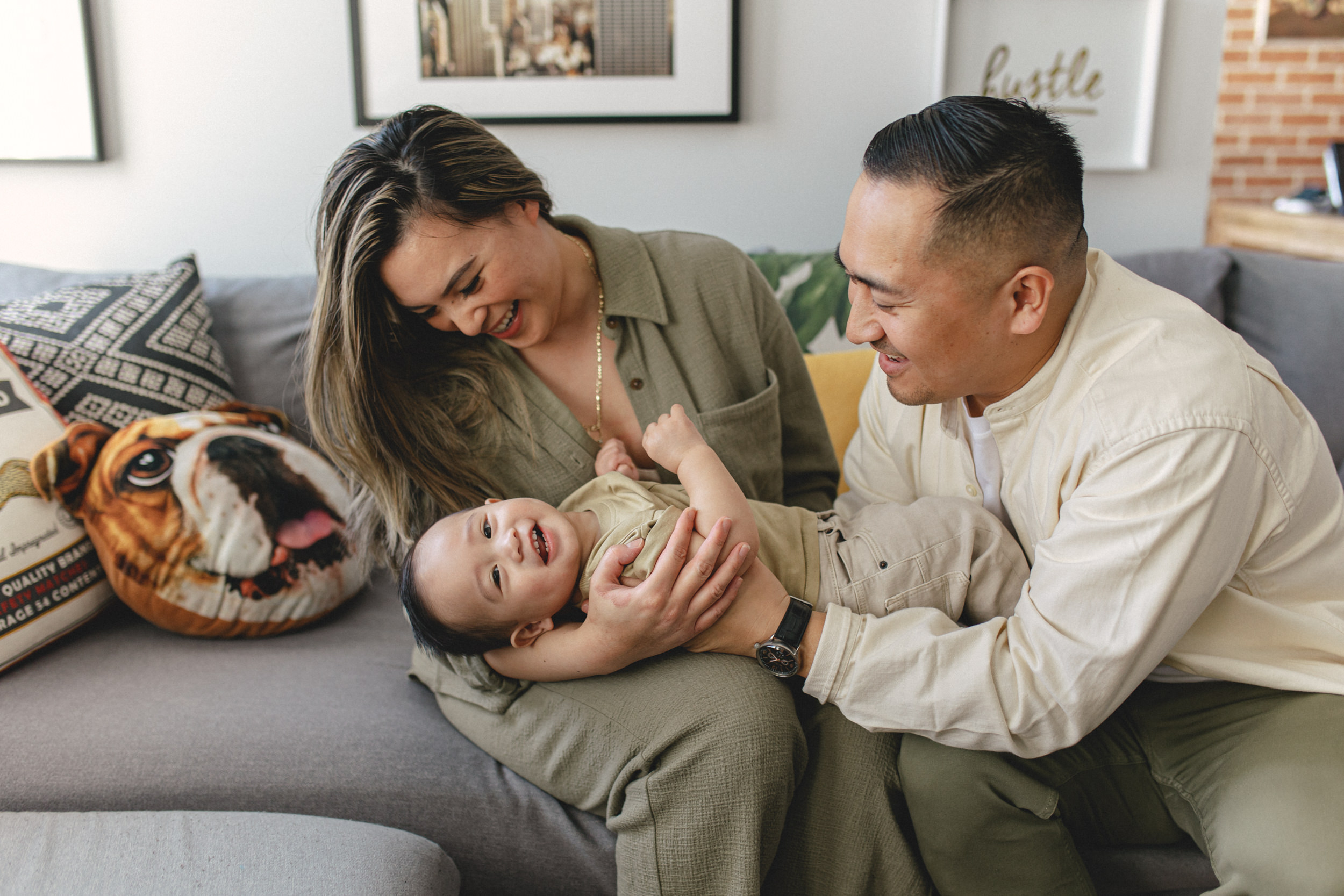Mother and father holding baby boy on couch